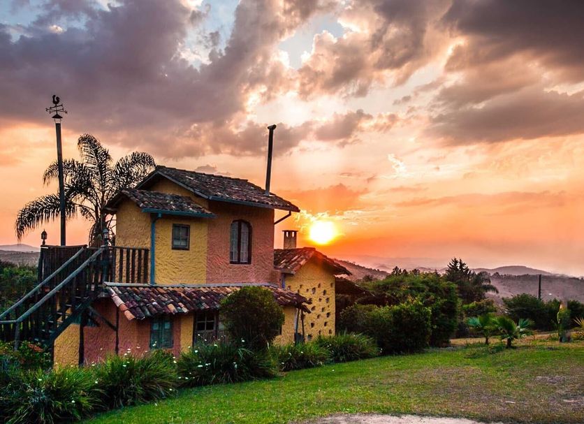 Capricho Asturiano in Santo Antônio do Leite at sunset, with rustic villa, palm trees and garden