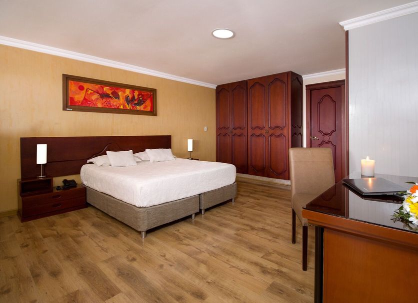 Hotel Luxor Pereira guest room in Pereira with a bed, wardrobe, desk, and wood-look flooring