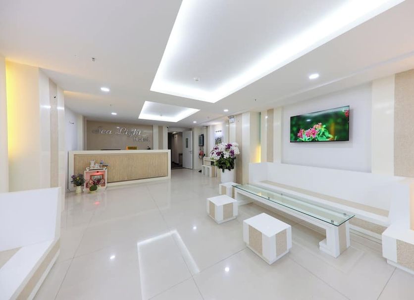Sea Light Hotel lobby in Nha Trang with white seating, glossy floors, reception desk and wall-mounted TV