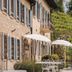 Locanda La Candola in Pieve di Soligo with stone facade, shutters, balcony, and outdoor café seating