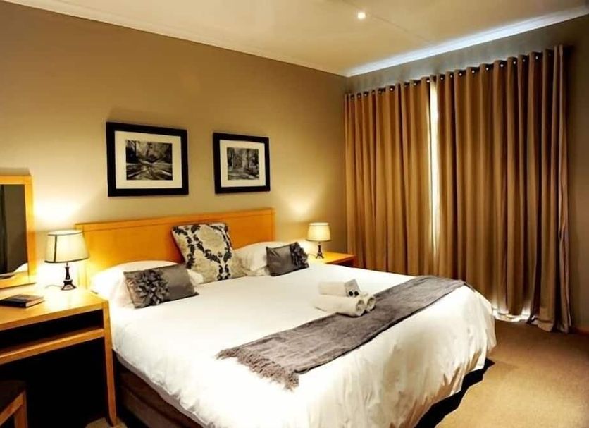 Villa Paradiso Country Manor Hartbeespoort guest room with king bed, bedside lamps and floor-to-ceiling curtains