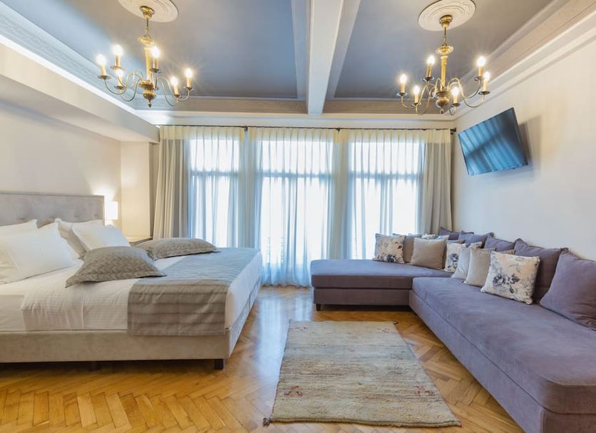 Sweet Home Hotel Athens guest room with bed, sectional sofa, chandelier lights and balcony doors