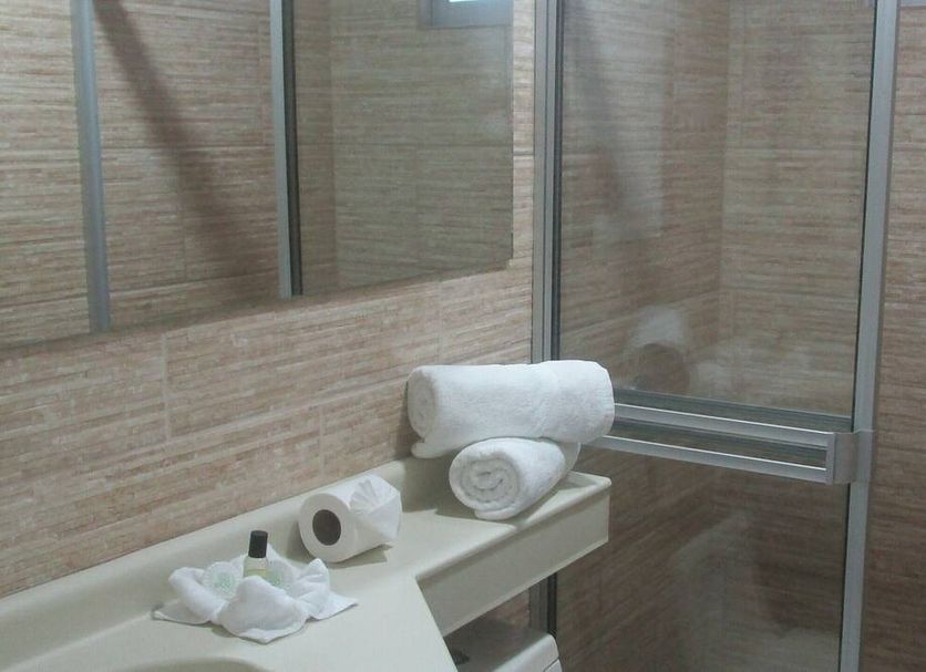 Hotel Sueño Tranquilo Quepos bathroom with bathtub, towels, toilet paper, and glass shower enclosure