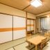 Kumano No Yado Umihikari guest room with tatami mats, low table, chairs, and large window curtains in Kumano