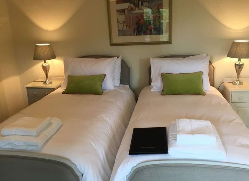 Castle Farm House B&B in Corby: twin beds with bedside lamps and folded towels in a cozy guest room