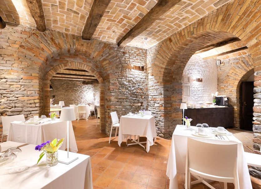 Relais Villa del Borgo Canelli dining room with stone arches, brick ceilings and white table settings