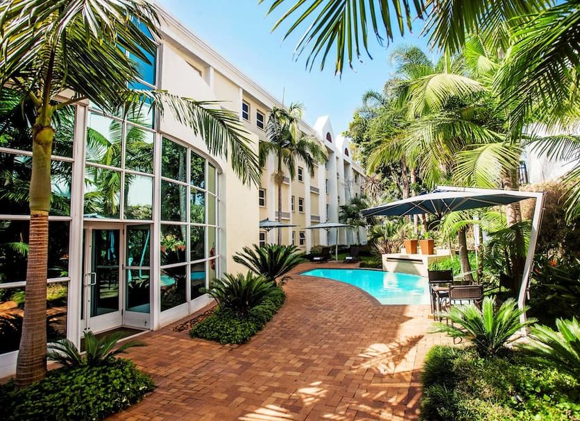 StayEasy Pretoria courtyard with palm trees, brick path and outdoor pool in Pretoria