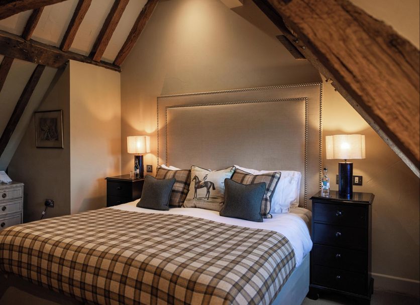 Wingrove House in Polegate: cozy attic bedroom with plaid duvet, exposed beams, and bedside lamps