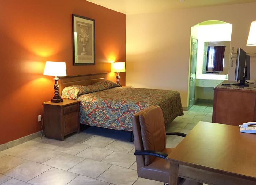 Boca Chica Inn and Suites Brownsville guest room with bed, lamps, desk, TV and tile floor