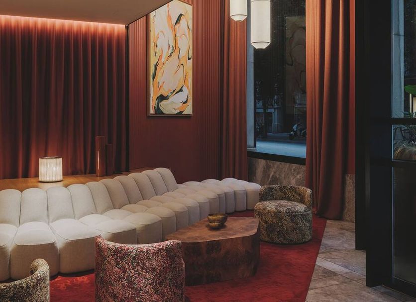 Catalonia Boulevard Barcelona lounge with curved cream sofa, red curtains, and city-view window