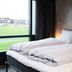 Hotel Guestapart in Aarhus guest room with twin beds beside a large window overlooking green views