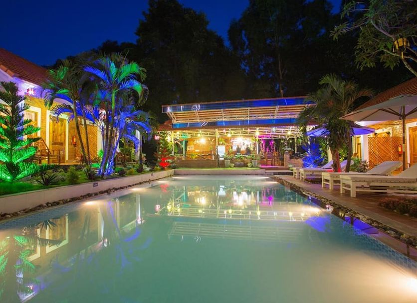 Little Garden Bungalow, Phu Quoc: illuminated outdoor pool with palm trees and lounge chairs at night