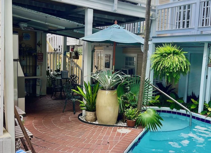 The Garden House in Key West courtyard with a small pool, potted tropical plants, and patio seating