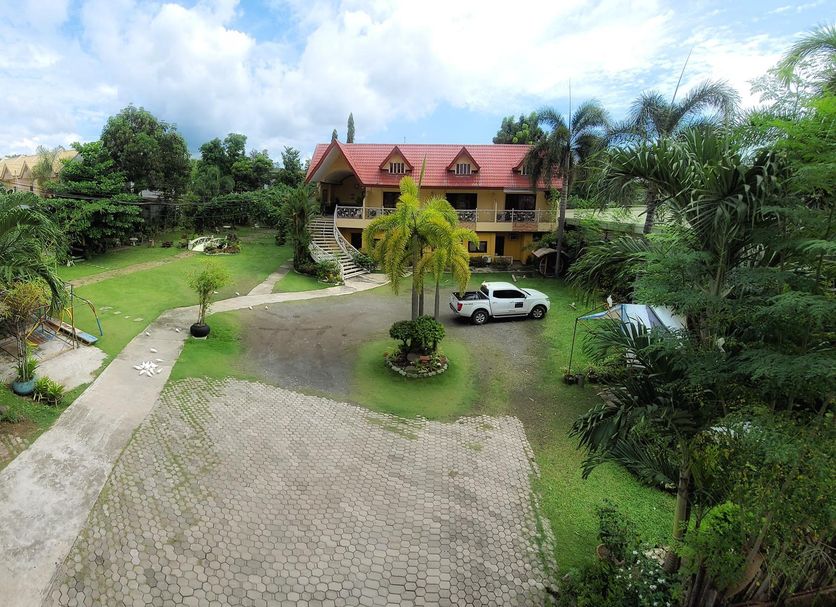 Sunny Point Hotel in Davao City with a landscaped driveway, palm trees, and parked vehicle