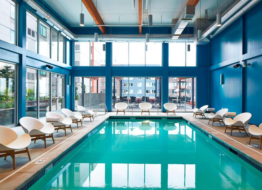 Aloft Seattle Redmond indoor pool with lounge chairs and large windows in Redmond