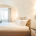 Teichnersuite Rome bedroom with brass bed, arched ceiling, sofa, and window seating