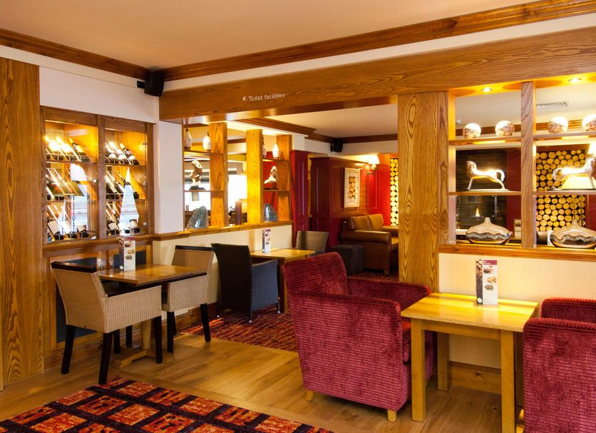 Premier Inn Rugeley lounge with seating, tables, warm lighting and display shelving