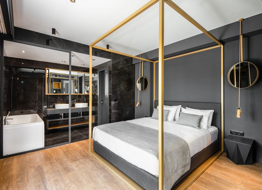 Colors Hotel Athens in Athens: modern room with gold canopy bed, black walls, and freestanding tub