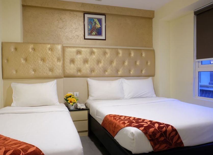 Sandpiper Hotel Singapore room with two beds, tufted headboard, and city view window