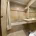 Narita Hotel Tulungagung bathroom with bathtub, sink vanity, toilet, and beige tile walls