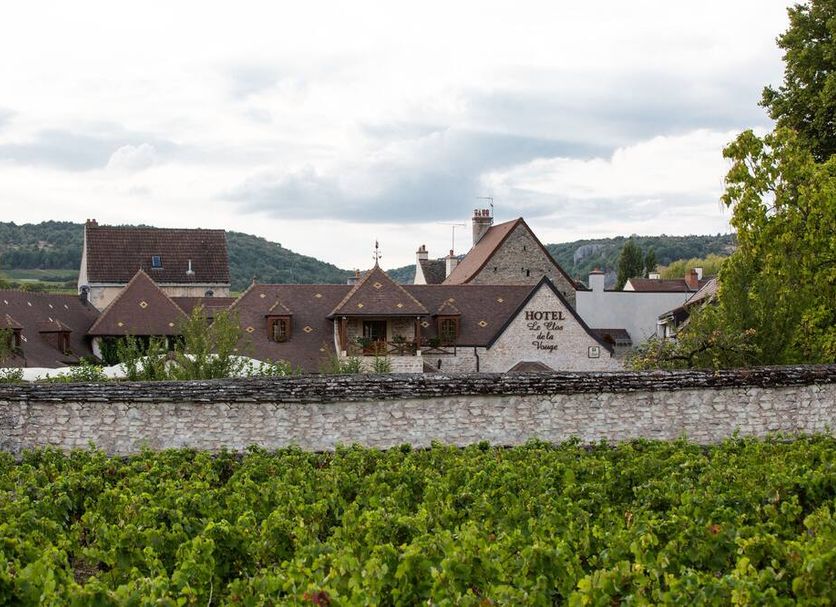 Hotel Le Clos De La Vouge in Vougeot with stone wall, vineyard, and village rooftops