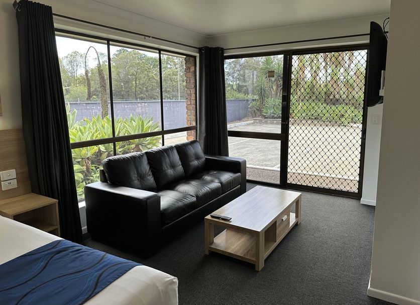 Logan City Motor Inn in Slacks Creek room with black sofa, coffee table and large window