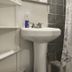 The Macaw Guesthouse in New York bathroom with pedestal sink, shower curtain, and open shelves