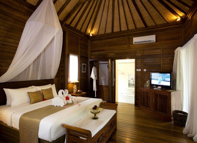 The Mansion Resort Hotel & Spa in Ubud guest room with four-poster bed and TV
