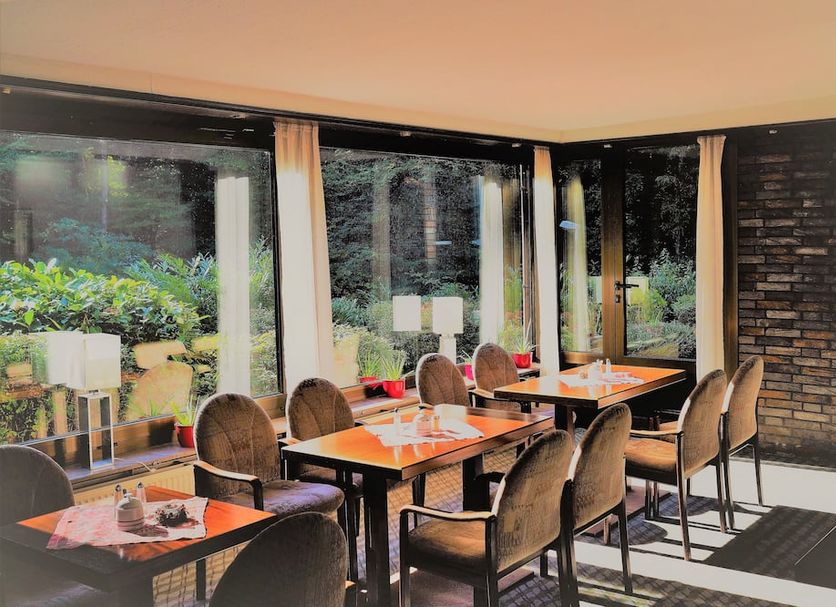 Waldhotel Porta Westfalica dining room with large windows and garden views in Porta Westfalica