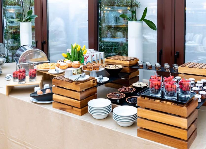 Breakfast buffet at Hotel Le Premier in Zagreb with pastries, fruit, yogurt and juice on wooden stands
