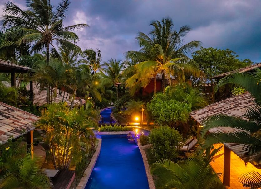 Domus Villas in Tibau do Sul with a glowing pool surrounded by lush tropical palms at dusk