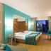 Terrace Elite Resort in Side guest room with king bed, teal accent wall, desk and balcony view