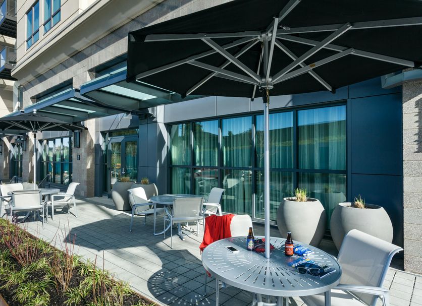 Hampton Inn & Suites Seattle/Northgate patio with tables, umbrellas and glass-front seating area