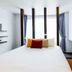 Raha Grand Hotel Patong room with bed, large window, blue curtains, and wall-mounted TV in Patong
