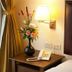 S.M. Grande Residence Bangkok room with bedside table, lamp, phone, and floral arrangement