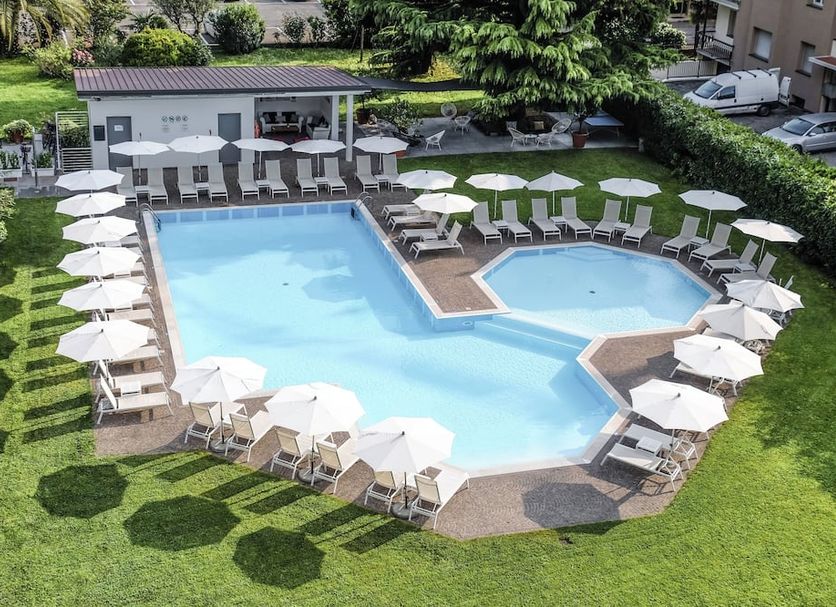 Hotel Luise in Riva del Garda: outdoor pool with sun loungers, umbrellas and landscaped garden
