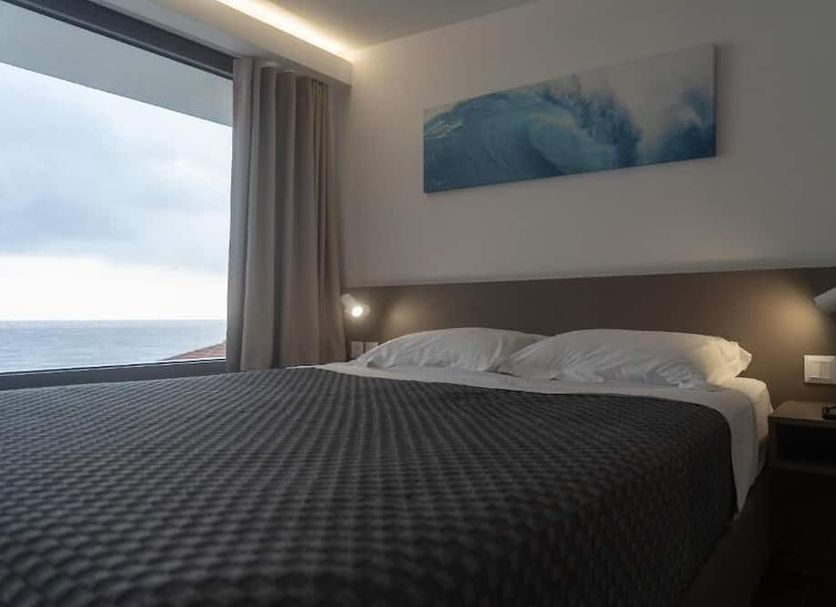 Olympos Suites Apartments in Leptokaryá: bedroom with ocean view through a large window