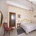 Soggiorno Burchi hotel room in Florence with wrought-iron bed, chandelier, desk and red chair