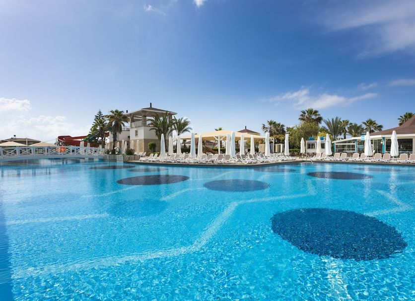 Orange County Belek in Belek with a large outdoor pool, palm trees, and sun loungers under a blue sky