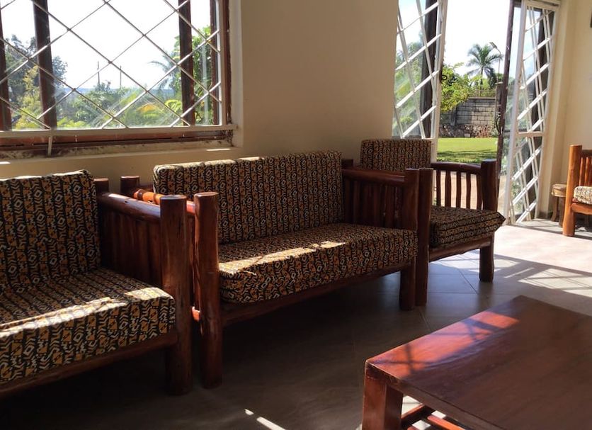 African Roots Guesthouse Entebbe lounge with woven sofas and open doors to the garden