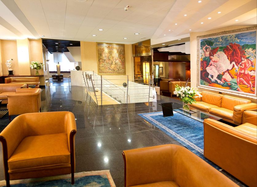 Qc Room Milano Porta Romana lobby in Milan with orange lounge chairs, glass staircase and modern art