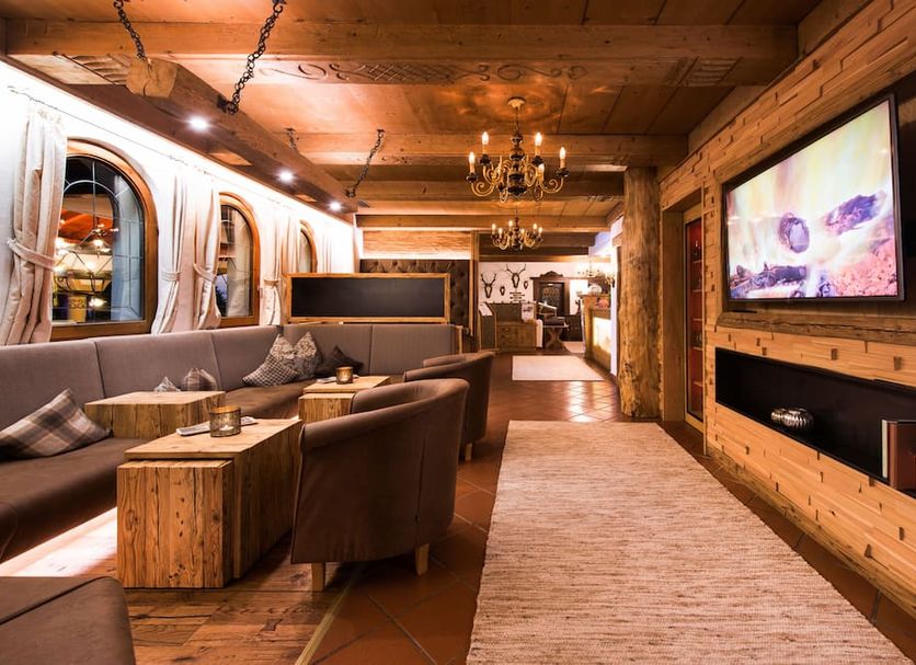Hotel Stubaierhof lounge in Neustift im Stubaital with rustic wood decor, seating, and wall-mounted TV