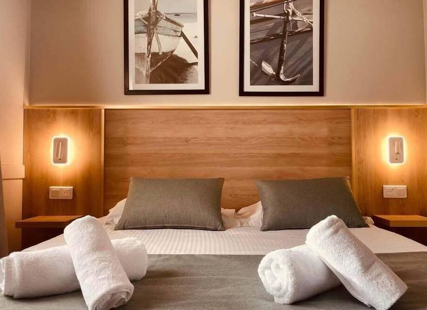 Le M Hotel & Spa Honfleur bedroom with wood headboard, twin lamps and rolled towels