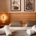 Le M Hotel & Spa Honfleur bedroom with wood headboard, twin lamps and rolled towels