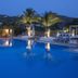 Dionysos Seaside Resort Ios in Mylopotas, poolside with palm trees and hillside views at dusk