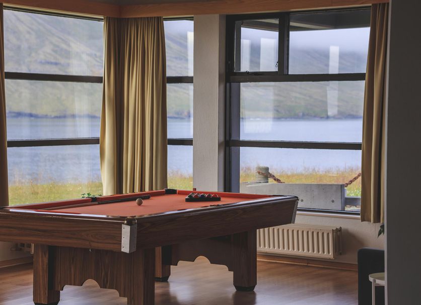 The Cliff Hotel in Neskaupstadur with a pool table and large windows overlooking the water