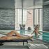 Four Seasons Hotel One Dalton Street, Boston indoor pool with city skyline views and a guest on a lounge chair