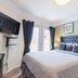 Newton Villa in Brampton guest room with king bed, wall-mounted TV, and French doors to outside