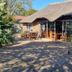 Emerald Guesthouse in Kempton Park with thatched-roof patio, outdoor tables and glass-fronted entrance