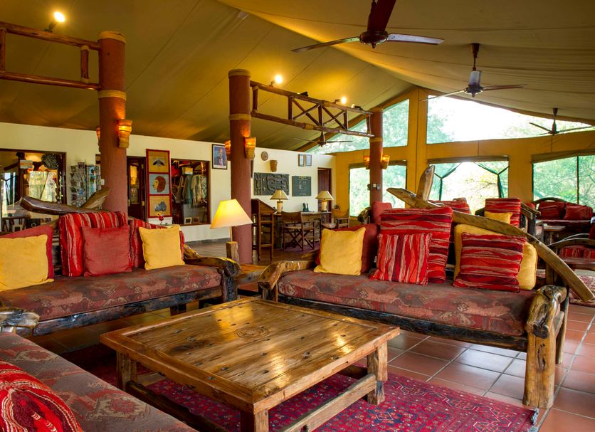 Mbuzi Mawe Serena Camp lounge in Serengeti with rustic sofas, wooden coffee table and large windows